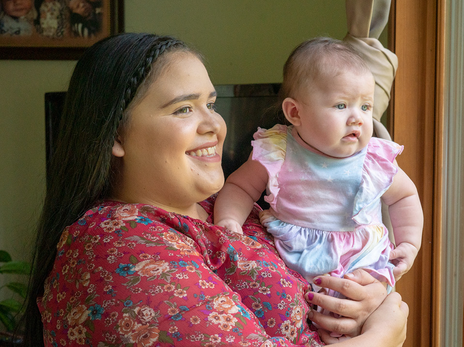 Woman Holds Baby as They Look Out Window