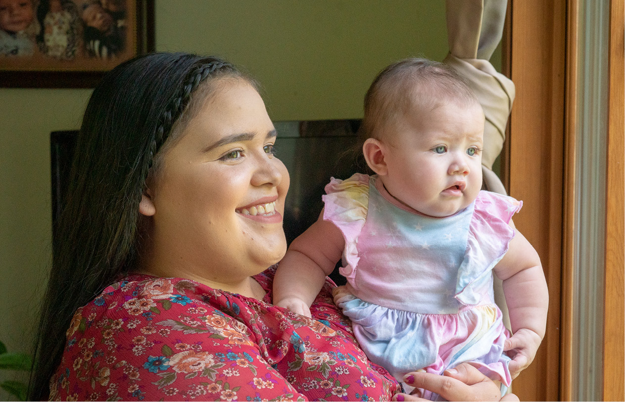 Woman Holds Baby as They Look Out Window