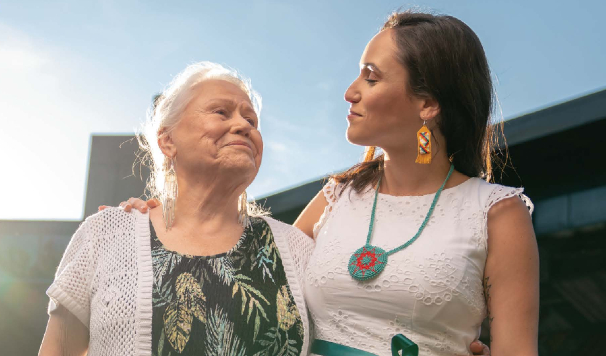 Elder and Adult Woman Wrap Their Arms Around Each Other and Smile